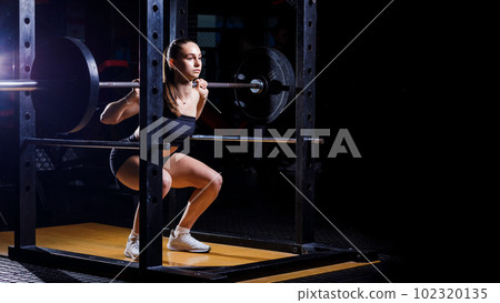 Personal Trainer Showing Young Woman How To Train Barbell Squats