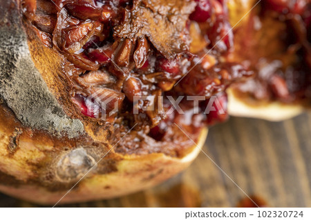 Rotten spoiled red ripe pomegranate on the board Rotten spoiled red ripe pomegranate on the board 102320724
