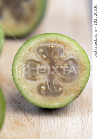 Green ripe feijoa cut in half on a board 102320836