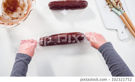 Step by step. Flat lay. Wrapping cookie dough into the plastic wrap to bake chocolate cookies. Step by step. Flat lay. Wrapping cookie dough into the plastic wrap to bake chocolate cookies. 102321752