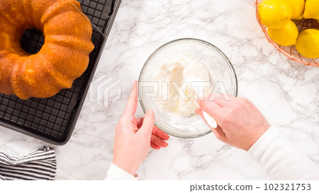 Flat lay. Step by step. Mixing ingredients in a glass mixing bowl to prepare lemon glaze for a lemon bundt cake. Flat lay. Step by step. Mixing ingredients in a glass mixing bowl to prepare lemon glaze for a lemon bundt cake. 102321753