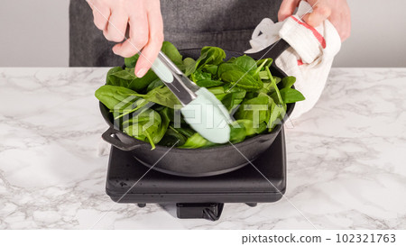 Step by step. Heating cast iron skillet over the stove to prepare spinach and ham frittata. Step by step. Heating cast iron skillet over the stove to prepare spinach and ham frittata. 102321763