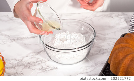 Step by step. Mixing ingredients in a glass mixing bowl to prepare lemon glaze for a lemon bundt cake. 102321772
