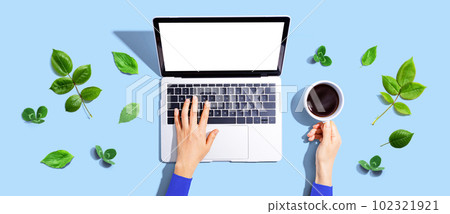 Person using a laptop computer with green leaves Person using a laptop computer with green leaves 102321921