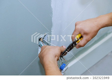 Electrician installing new current socket working safely in new house construction site Electrician installing new current socket working safely in new house construction site 102321949