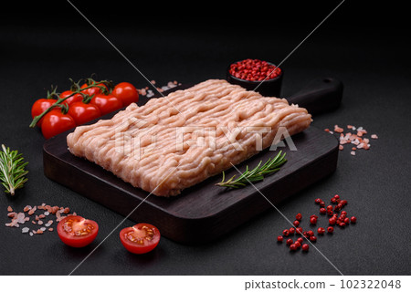 Fresh minced chicken with salt, spices and herbs on a wooden cutting board 102322048