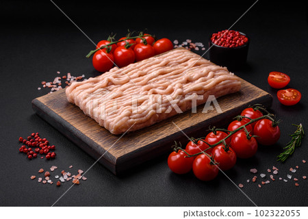 Fresh minced chicken with salt, spices and herbs on a wooden cutting board Fresh minced chicken with salt, spices and herbs on a wooden cutting board 102322055
