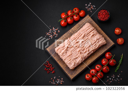Fresh minced chicken with salt, spices and herbs on a wooden cutting board 102322056