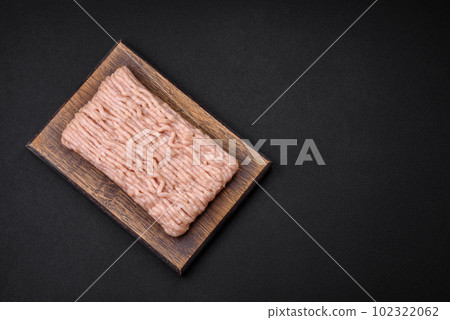 Fresh minced chicken with salt, spices and herbs on a wooden cutting board 102322062