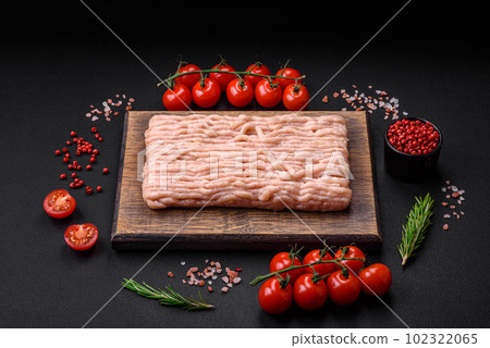 Fresh minced chicken with salt, spices and herbs on a wooden cutting board Fresh minced chicken with salt, spices and herbs on a wooden cutting board 102322065