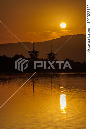 Western Kyoto dyed in gold with the sun announcing the beginning of the day over Yakushiji as the sun rises 102322113
