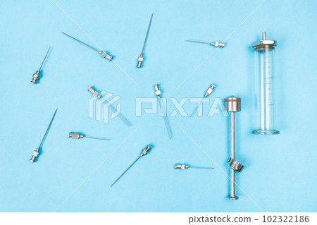 steel hypodermic needles and glass syringe on blue 102322186