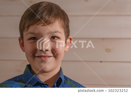Portrait of a boy 8 years old brunette in a blue shirt. Smiling with closed lips. 102323252