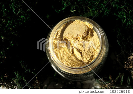 An open jar of a yellow turmeric facial scrub showing off its texture. 102326918