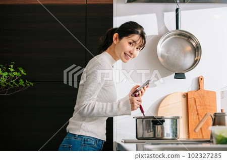烹調的婦女,當觀看智能手機時 烹調的婦女,當觀看智能手機時 102327285