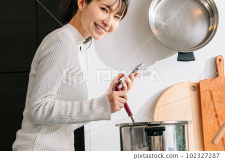 烹調的婦女,當觀看智能手機時 烹調的婦女,當觀看智能手機時 102327287