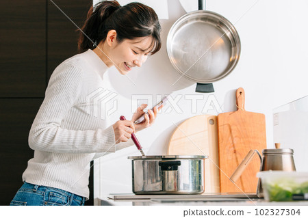 烹調的婦女，當觀看智能手機時 102327304