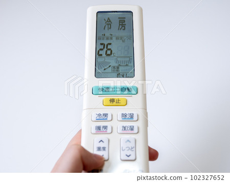A woman's hand setting the cooling temperature with the remote control of the air conditioner (setting 26 ℃) A woman's hand setting the cooling temperature with the remote control of the air conditioner (setting 26 ℃) 102327652