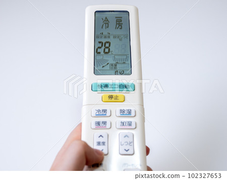 一位女士的手用空調遙控器設置冷卻溫度（設置 28°C） 102327653