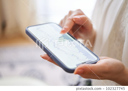 A woman's hand checking the exchange chart on her smartphone A woman's hand checking the exchange chart on her smartphone 102327745