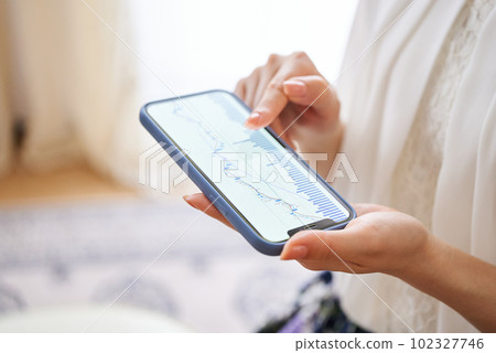 A woman's hand checking the exchange chart on her smartphone A woman's hand checking the exchange chart on her smartphone 102327746