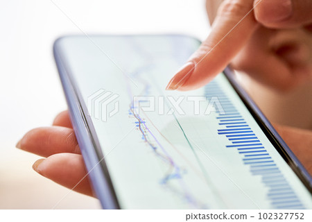 A woman's hand checking the exchange chart on her smartphone 102327752
