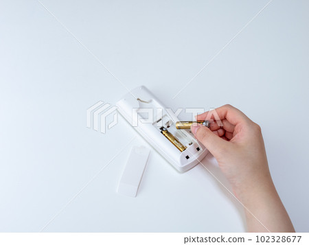 更換遙控器電池(AAA 電池)的女士手 更換遙控器電池(AAA 電池)的女士手 102328677