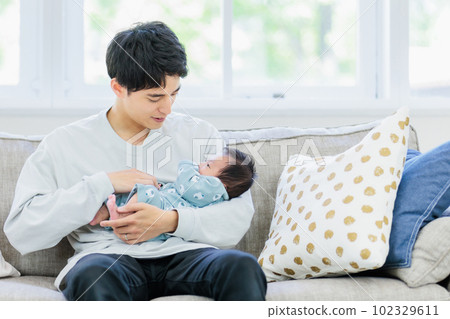 Dad holding a baby on the sofa Dad holding a baby on the sofa 102329611