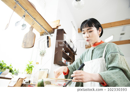 Young woman making pumpkin pancakes 102330393