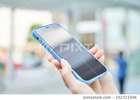 Hand of a woman using a smartphone on a street corner Hand of a woman using a smartphone on a street corner 102331946