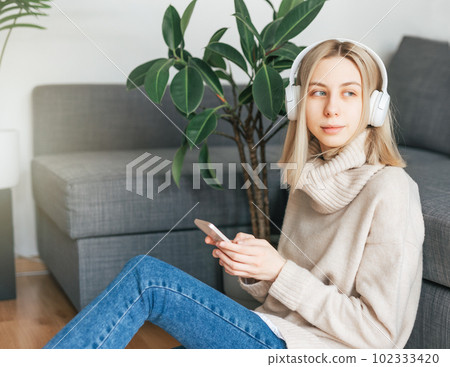 Young caucasian woman relaxes at home with music Young caucasian woman relaxes at home with music 102333420