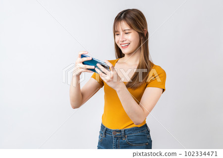 Excited young Asian woman playing games with smartphone on white background. Excited young Asian woman playing games with smartphone on white background. 102334471