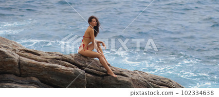 Epic Scene Aerial Drone View of Bikini Woman Model on a Rock at the Sea 102334638