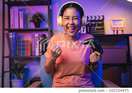 Excited Young Asian woman holding joysticks with playing online game. Excited Young Asian woman holding joysticks with playing online game. 102334975