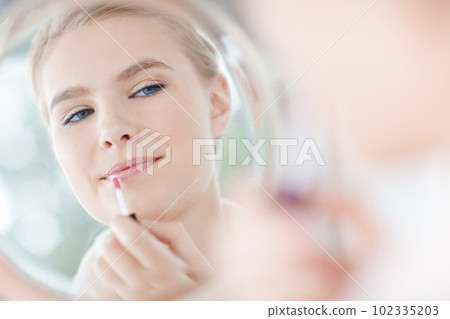 Getting ready for her big date. a reflection of a woman putting on her lipgloss in the mirror. Getting ready for her big date. a reflection of a woman putting on her lipgloss in the mirror. 102335203