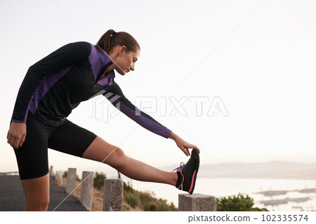 Alway stretch before exercise. a young woman stretching before a run. 102335574