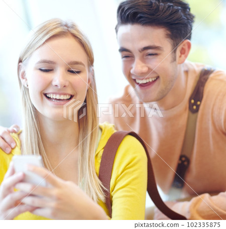 Laughing at the phone together. Young teen couple reading texts on a cellphone. 102335875
