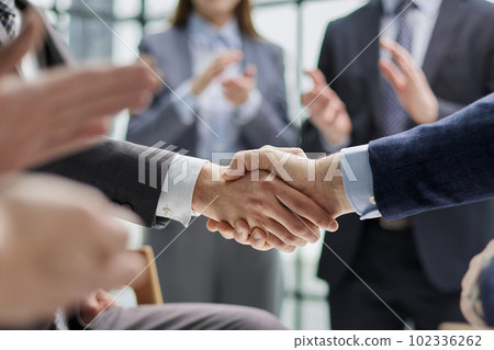 Business colleagues shaking hands in an office hallway 102336262