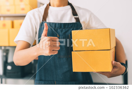 Owner holding packing box with showing thumb up,like sign, best,working at the home office Owner holding packing box with showing thumb up,like sign, best,working at the home office 102336362