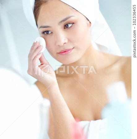 Keeping those wrinkles at bay...An attactive young Asian woman applying moisturizer with a towel on her head. 102336455