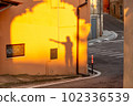 Shadow of a pointing man on an orange wall in the village of Cossignano in Italy. 102336539