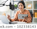 woman holding digital tablet and use microphones wear headphones with laptop. 102338143