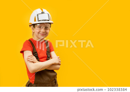 Portrait of teenager wears protective helmet glasses and jumpsuit like worker or construction worker on yellow background. Copy space. 102338384