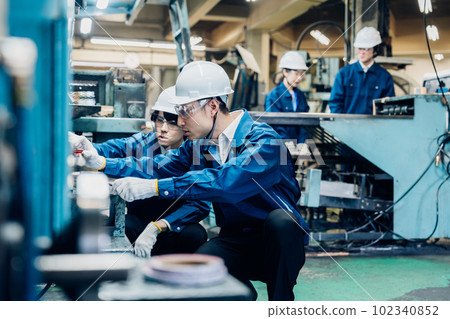 Workers servicing machinery in a factory Workers servicing machinery in a factory 102340852