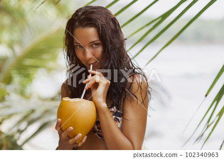 Close-up of a Drinking Beach Girl a Coconut Cocktail on a Tropical beach During Summer Vacation 102340963