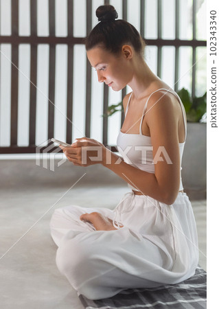 Smart Moves: Attractive Woman Multitasking with Phone During Yoga Practice Smart Moves: Attractive Woman Multitasking with Phone During Yoga Practice 102343340