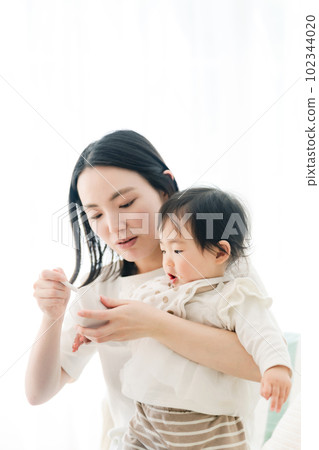 Mama feeding baby food to baby 102344020