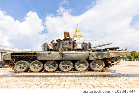 A wrecked rusty Russian tank against the backdrop of a blue sky and the golden dome of the bell tower of St. Michael's Cathedral is on display in Kyiv. Ukraine. 102345444
