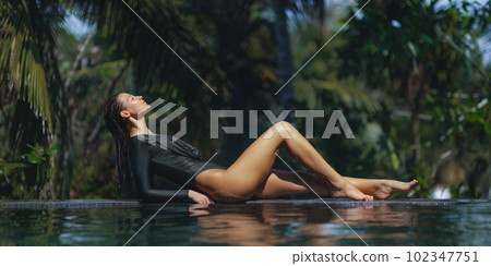 Swimsuit Model Relaxing in Infinity Swimming Pool at Luxury Villa Hotel in High-end Resort. Swimsuit Model Relaxing in Infinity Swimming Pool at Luxury Villa Hotel in High-end Resort. 102347751