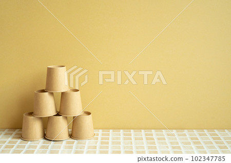 Pyramid stack of brown cup on desk. yellow background. business develop achievement growth concept Pyramid stack of brown cup on desk. yellow background. business develop achievement growth concept 102347785